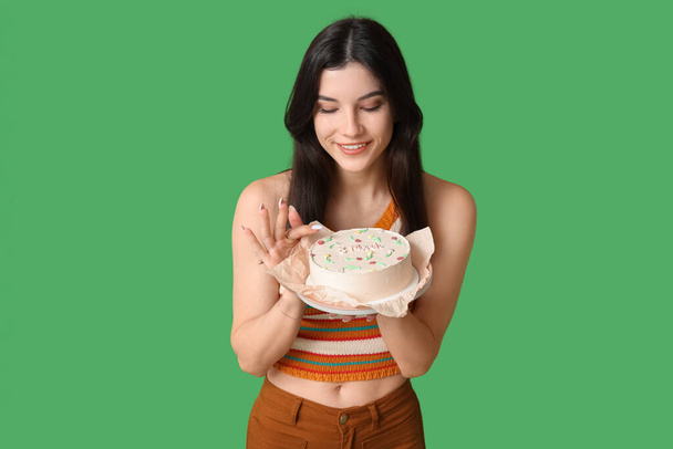 Mooie jonge vrouw met zoete bento cake op groene achtergrond. Internationale Vrouwendag - Foto, afbeelding