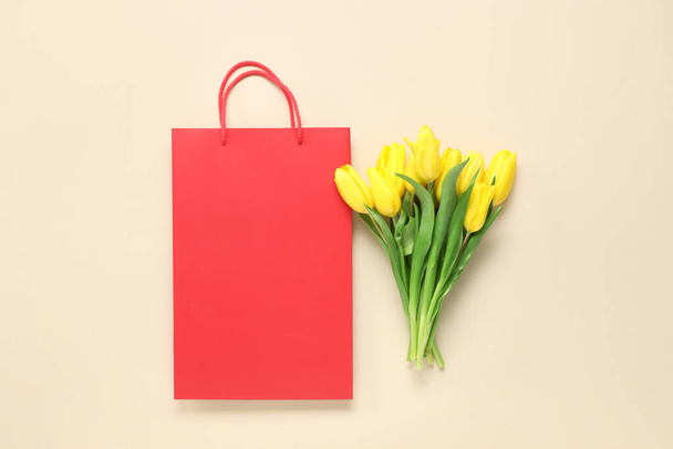 Bolsa de compras de papel con tulipanes amarillos sobre fondo beige - Foto, Imagen
