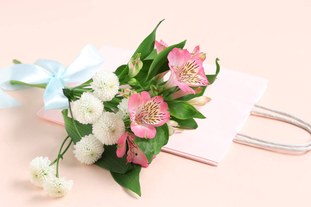 Shopping bag di carta con fiori e nastro su sfondo beige - Foto, immagini
