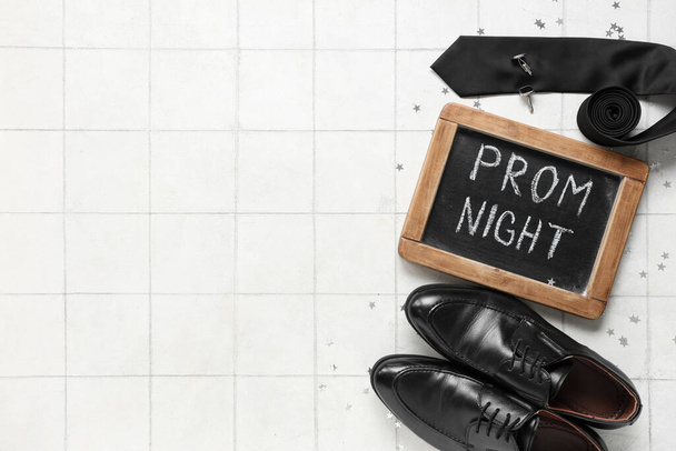Доска с текстом ПРОМ ночь, мужская обувь и галстук на белом фоне плитки - Фото, изображение