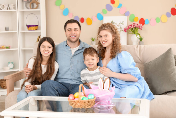 Счастливая семья сидит за столом с пасхальными яйцами дома - Фото, изображение