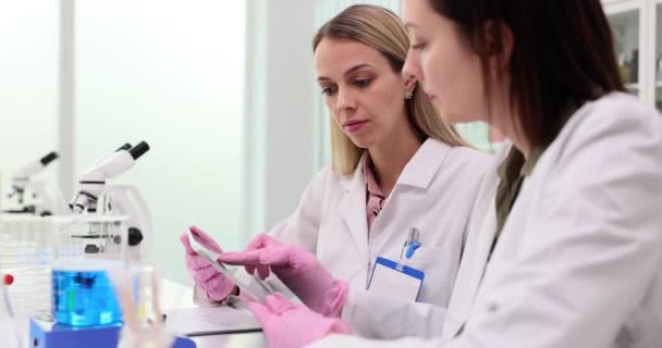 Farmacêuticas femininas verificam os resultados dos testes em comprimidos em câmara lenta de laboratório. Estudantes de medicina concentrada criar relatórios on-line de pesquisa de acabamento em clínica - Filmagem, Vídeo