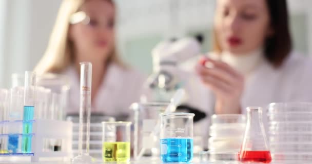 Glaskolben mit farbigen Flüssigkeiten und Wissenschaftlerinnen, die im chemischen Labor arbeiten. Medizinstudenten testen verschiedene Materialien mit Technik - Filmmaterial, Video