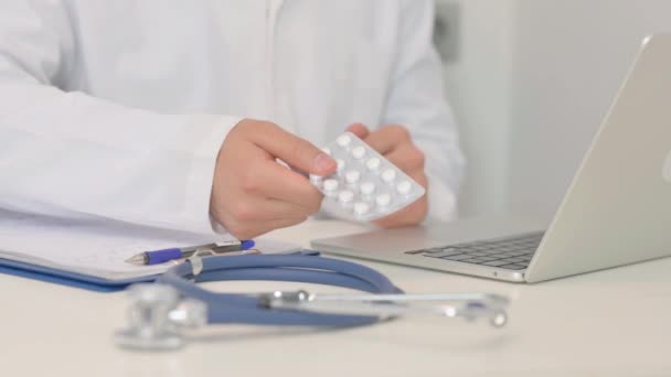 Primer plano del médico mostrando la tira blanca de píldoras cerca del ordenador portátil - Metraje, vídeo