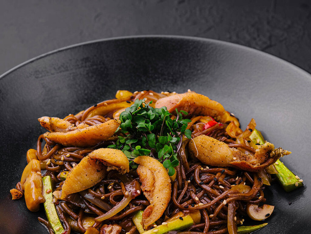 Chinesische gebratene Buchweizen-Nudeln mit Fleisch auf schwarzem Teller - Foto, Bild