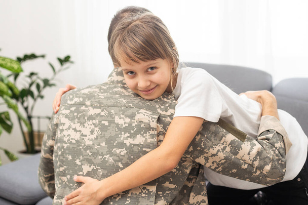 Niña abrazando a su padre militar en casa, de cerca. Foto de alta calidad - Foto, imagen
