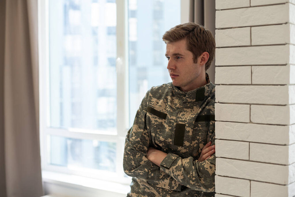 Portret van een militair die diep in gedachten zit en zich bedroefd voelt. - Foto, afbeelding