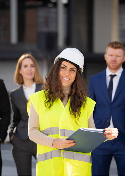 Muotokuva hymyilevä onnellinen nainen rakennusarkkitehti asiakkaiden johtajat takana. Naisten johtamisen ja johtamisen käsite. - Valokuva, kuva