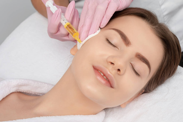 Cosmetologist faz prp terapia no rosto de uma mulher bonita em um salão de beleza. Conceito de cosmetologia. - Foto, Imagem