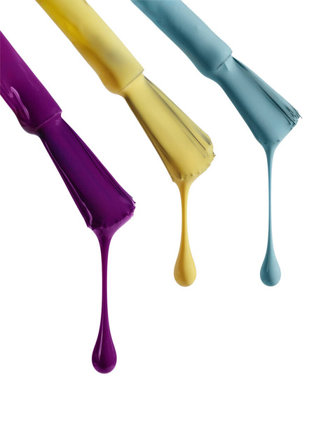 Variedad de gotas de esmalte de uñas multicolores que fluyen del cepillo aislado sobre fondo blanco. Conjunto de muestras de esmalte de uñas de gel para diseño. - Foto, Imagen