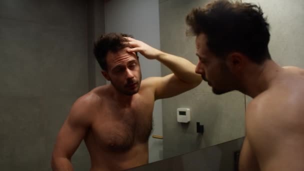 Kaukasischer Mann überprüft Haarzustand im Badezimmer - Filmmaterial, Video