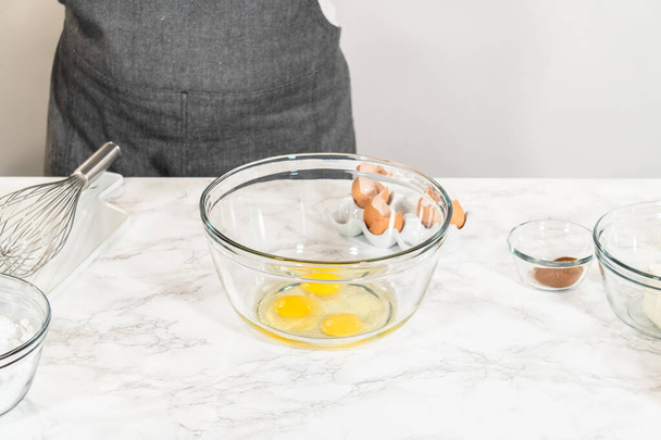 En un tazón de vidrio grande, los ingredientes se mezclan expertamente para crear la masa para hornear el delicioso pastel de zanahoria Bundt. - Foto, Imagen