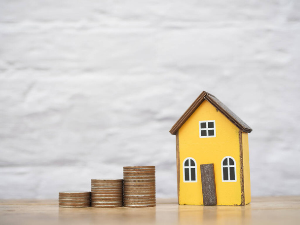 Miniaturhaus und Stapel von Münzen. Das Konzept des Sparens Geld für Haus, Immobilieninvestitionen, Haus Hypothek, Immobilien - Foto, Bild