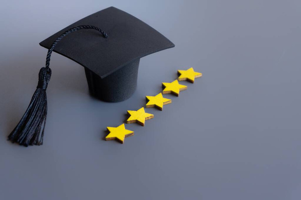 Graduation cap naast een rij van vijf sterren waardering op een grijze achtergrond. Kopieer ruimte voor tekst. Het concept van het beste onderwijsstelsel. - Foto, afbeelding