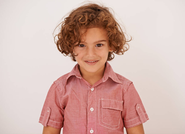 Smile, fashion and boy child in studio with casual, trendy and cool shirt for outfit with curly hair. Happy, cute and portrait of adorable young kid model with style isolated by white background - Photo, Image