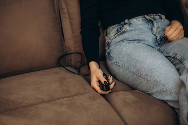 женщина с помощью пульта дистанционного управления открывает подставку для ног на диване - Фото, изображение