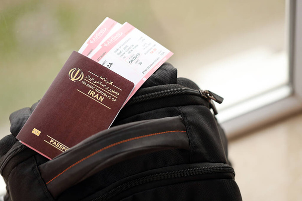 Passaporte vermelho da República Islâmica do Irã com passagens aéreas na mochila turística de perto. Turismo e conceito de viagem - Foto, Imagem