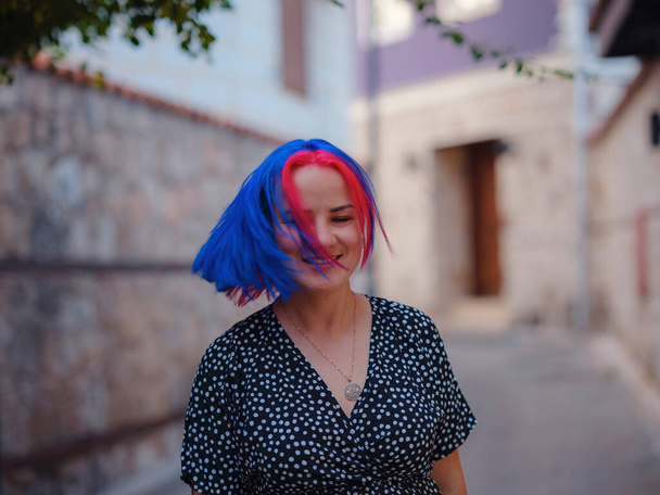 female summer old town walk in Antalya Turkey. woman with colorful hair and dress gracefully explores its historic streets. creating visual symphony that harmonizes past and present. - Photo, Image