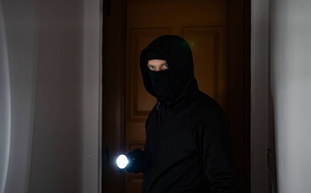 Ladrón enmascarado con linterna de control de la antorcha apartamento. - Foto, imagen