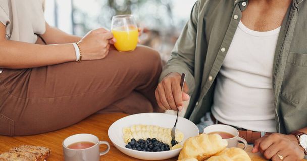 Egészség, kéz és pár eszik reggelit gyümölccsel, kávéval és gyümölcslével az asztalnál a wellness diéta. Étel, wellness és közelkép a férfi és nő élvezi villásreggeli együtt otthon - Fotó, kép