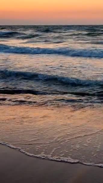 Fırtınalı deniz. Gün batımında ve şafakta denizde beyaz köpüklü büyük dalgalar. Mavi deniz, turuncu kırmızı gökyüzü. Sahil kıyısı kıyı şeridi. Doğal arkaplan doğa fırtına düşey - Video, Çekim