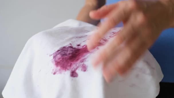 De handen tonen vlekken van bessen of inkt op een witte doek. Verwende kleren. Vuile vlek voor schoonmaakconcept. Hoge kwaliteit 4k beeldmateriaal - Video