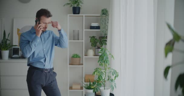 Αυτοπεποίθηση νεαρός επιχειρηματίας συζητά στρατηγική για κλήση μέσω κινητού τηλεφώνου, ενώ στέκεται με το χέρι στην τσέπη στο χώρο εργασίας - Πλάνα, βίντεο