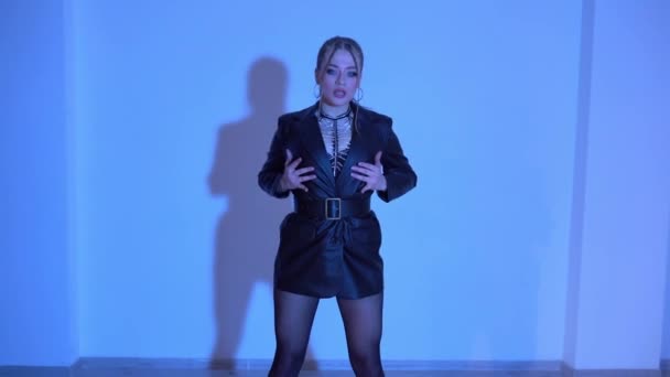 Sexy žena v vysokých podpatcích a černých kožených šatech tančí na podlaze v modře osvětlené místnosti. Vysoce kvalitní FullHD záběry - Záběry, video
