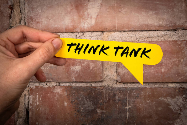 Think tank. Yellow speech bubble with text on a red brick background. - Photo, Image