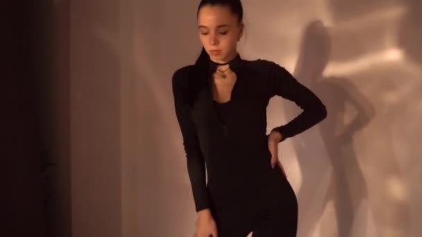 Fille sexy en vêtements noirs dansant en studio avec fond clair, danse en studio, ralenti. Des images FullHD de haute qualité - Séquence, vidéo