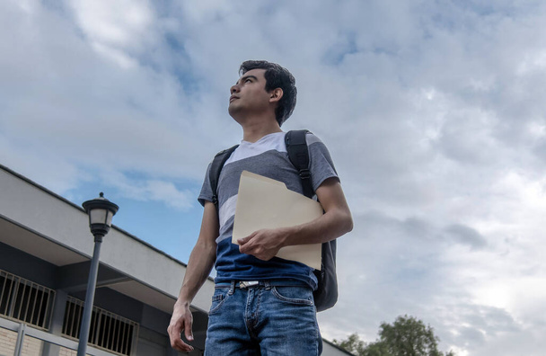 Άντρας φοιτητής κρατώντας ένα αρχείο και κοιτάζοντας ψηλά στον ουρανό - Φωτογραφία, εικόνα