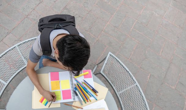 Студент-мужчина пишет в блокноте в школе - Фото, изображение
