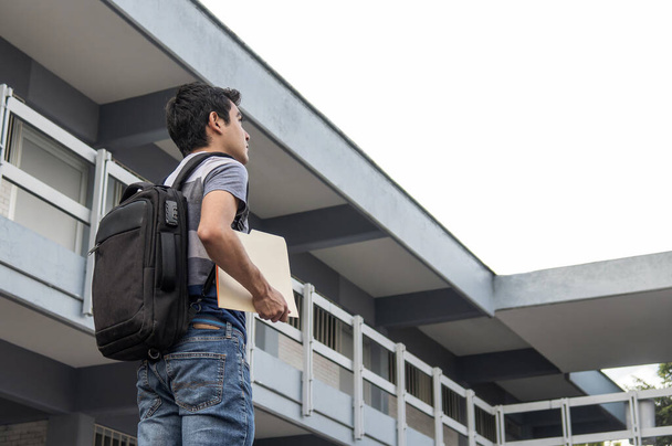 Μαθητής με ένα έγγραφο συγκράτησης σακίδιο και κοιτάζοντας προς το σχολείο - Φωτογραφία, εικόνα
