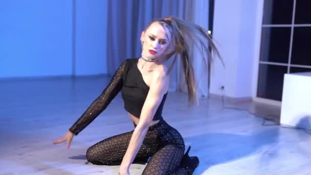 Sexy Mädchen in Top und Tanzhose tanzt auf dem Boden des beleuchteten Studioraums. Hochwertiges FullHD-Filmmaterial - Filmmaterial, Video