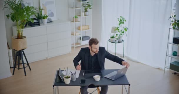 Woedende jonge zakenman sluiten laptop en scheuren papier terwijl weg te lopen van het bureau in corporate werkruimte - Video