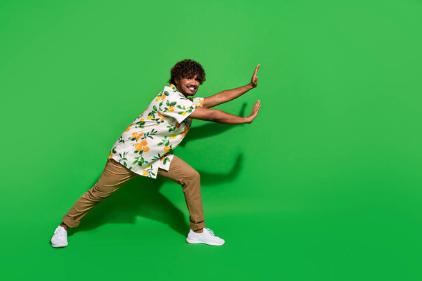 Full size photo of pretty young male push hard empty space wear trendy citrus print outfit isolated on green color background. - Φωτογραφία, εικόνα