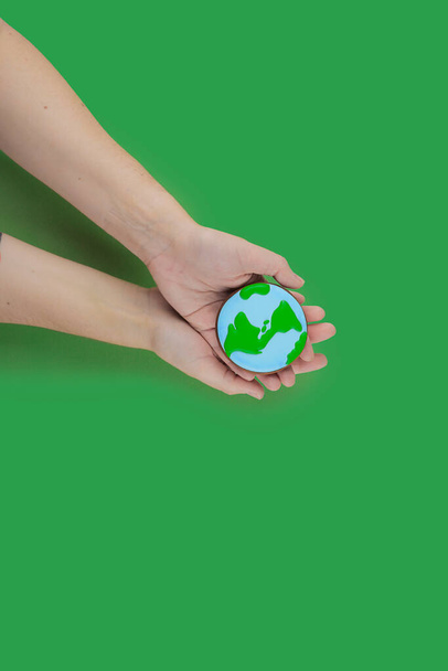 Earth Day concept. Cookie in shape of Earth in hand. - Photo, Image