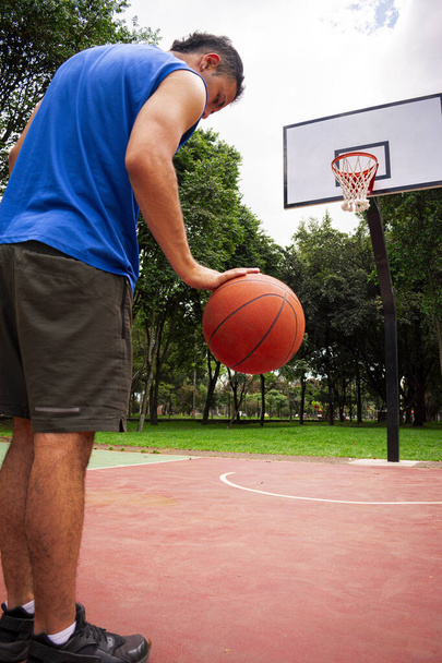 Мужчина тренирует баскетбол на корте в солнечный день летом  - Фото, изображение