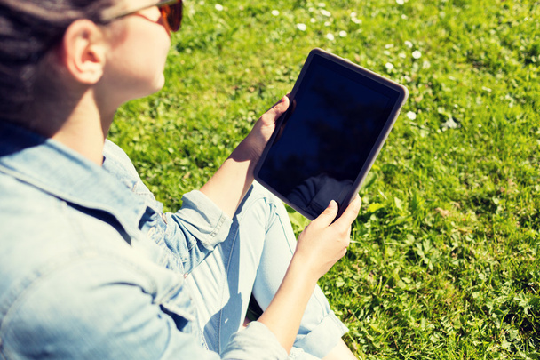 primer plano de la chica con la tableta de la PC sentado en la hierba
 - Foto, imagen