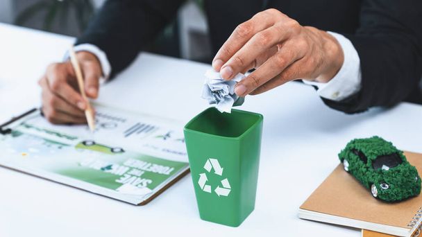 Geschäftsmann legte Papierabfälle in kleine, winzige Wertstofftonnen in seinem Büro und symbolisierte damit die Bemühungen der Unternehmen um eine umweltfreundliche Abfallwirtschaft durch Recycling für eine umweltfreundlichere Umwelt und null Umweltverschmutzung. Kreisel - Foto, Bild