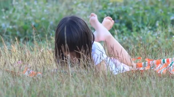 Dziewczyna z ekranem dotykowym leżąc na trawie w zachód światło - Materiał filmowy, wideo