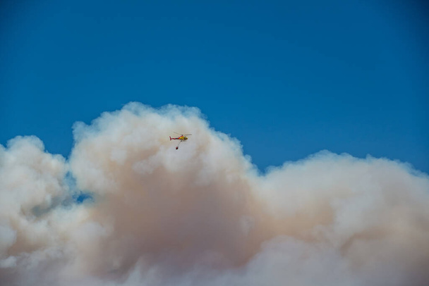 Büyük bir yangında uçan yangın helikopterinin panoramik görüntüsü mavi gökyüzüne yükseliyor (iklim değişikliği) (Curacav, Şili)) - Fotoğraf, Görsel