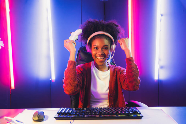 Afrikkalainen amerikkalainen tyttö pelaamista streamer joukkue voittaja pelaa verkossa taistelevat Esport yllään kuulokkeet neon valaistus huone. Puhuminen muut pelaajat höyläys strategioita voittaa kilpailijoita. Maustevalmistaja. - Valokuva, kuva