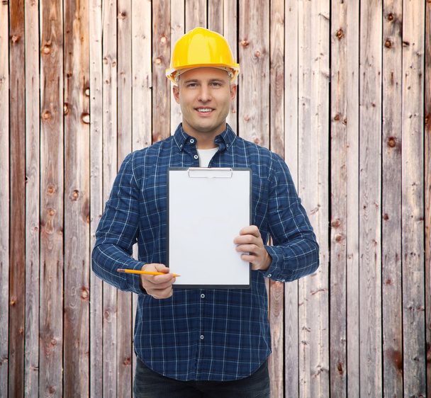 smiling male builder in helmet with clipboard - Foto, Bild