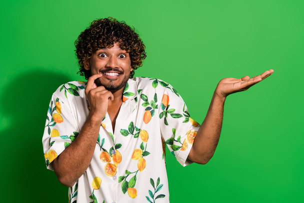 Photo of tricky impressed arabian man wear print shirt finger mouth holding arm empty space isolated green color background. - Φωτογραφία, εικόνα