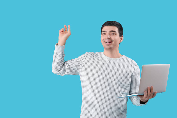 Программист-мужчина с ноутбуком, указывающий на что-то на синем фоне - Фото, изображение
