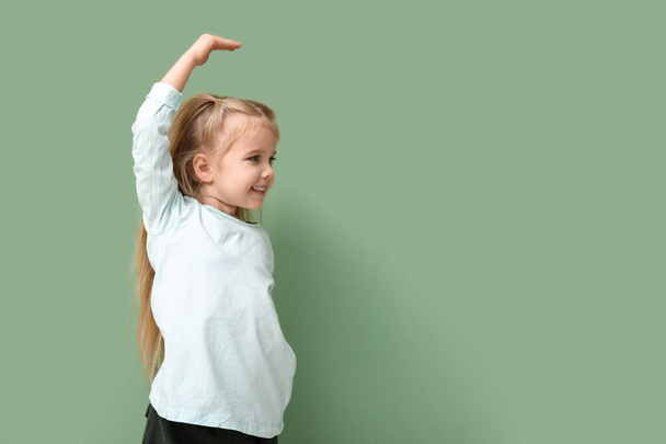 Cute little girl mierzy wysokość na zielonym tle - Zdjęcie, obraz