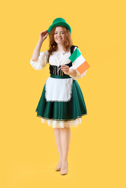 Νεαρή Ιρλανδή σερβιτόρα με σημαία σε κίτρινο φόντο. Γιορτή του Αγίου Πατρικίου - Φωτογραφία, εικόνα