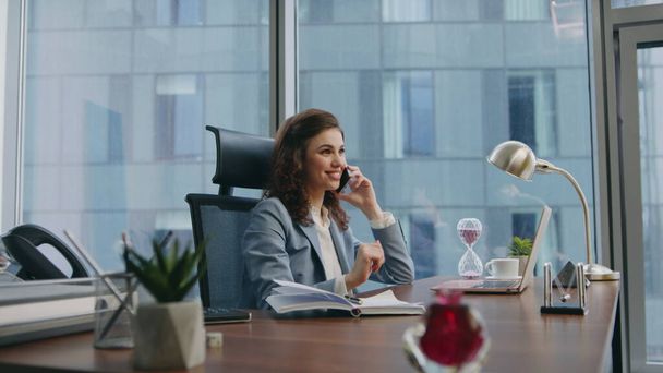 Girl consultant talking phone sitting luxury office close up. Elegant successful woman manager consulting client working at laptop on desk. Smiling businesswoman enjoy pleasant telephone conversation. - Photo, Image