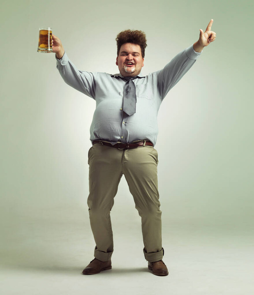 Happy man, portret en feest met bier voor feest of obesitas op een studio achtergrond. Jonge mannelijke persoon of plus size model met glas, mok of alcohol in tevredenheid voor drank op mockup ruimte. - Foto, afbeelding